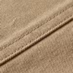 Close-up of the stone cotton twill weave and stitched seam of the Berg work jacket