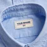 Close-up of the boys long sleeve shirt inside back neck with woven YOUR BRAND label and collar stitching