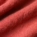 Close-up of the red cotton single jersey knit of the children's t-shirts, showing the yarn loops and natural fibres