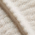 Close-up of the ivory cotton rib knit of the camisole, showing the fine vertical rib columns and natural yarn texture