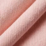 Close-up of the blush pink cotton single jersey showing the fine knit stitch columns, yarn fibres and a soft fold