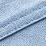 Close-up of the light blue pinpoint oxford cloth showing the fine basket weave, individual warp and weft threads and a felled seam