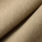 Close-up of the khaki cotton twill cloth of the twill jacket with the diagonal weave ribs, yarns and fibre hairs across a soft fold