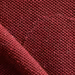 Close-up of burgundy cotton pique knit showing the raised knit cells, yarns and fine natural fibres of the heavyweight work polo fabric