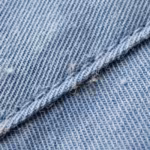 Close-up of the ceil blue poly-cotton twill weave of the men's zip pocket scrub tops, showing the diagonal rib, individual yarns, natural fibres and a felled seam