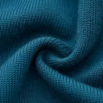 Close-up of the deep teal swim knit, showing the fine interlock stitch loops, yarn structure and fibre hairs across a soft fold