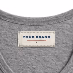 Close-up of the inside back neck of the men's grey marl tank top showing the cream woven YOUR BRAND label with navy lettering, a red rule line and the size M mark, stitched into the inside back neck just below the bound neckline binding