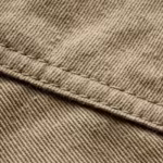 Khaki cotton twill fabric close-up showing the diagonal weave and a felled seam