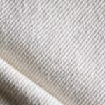 Close-up of the white poly-cotton twill weave of the chef uniform, showing the diagonal ribs and yarn structure