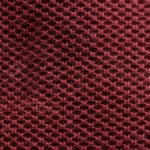 Close-up of burgundy cotton pique knit showing the raised knit cells, yarn loops and fine natural fibres of the polo fabric