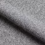 Close-up of the grey marl performance knit of the gym clothing, showing the interlock stitch loops, heathered yarn fibres and a soft fold