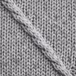 Close-up of light grey marl jumper knit showing stocking stitch V columns, twisted yarns and heathered fibres, with a diagonal cable stitch crossing the frame