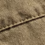 Close-up of the khaki cotton twill weave of the casual shorts, showing the diagonal weave, yarns and a stitched seam