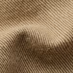 Close-up of khaki cotton twill cloth showing the fine diagonal ribs, individual yarns and fibre hairs across a soft fold