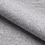 Close-up of the grey marl cotton single jersey of the men's underwear, showing the fine knit loops, heathered yarns and fibre hairs over a soft fold