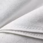 Close-up of the white poly-cotton poplin weave of the men's zipper smock lab coats, showing the plain weave, individual yarns, natural fibres and a felled seam