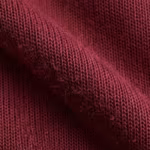 Close-up of burgundy tricot tracksuit cloth across a soft fold, showing the fine warp-knit columns, yarn loops and fibre hairs of the smooth matte face